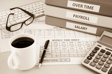 payroll documents and financial binders sit on a desk
